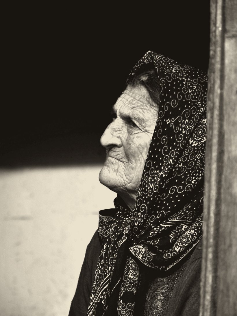 An older woman by a window, in quiet thought.